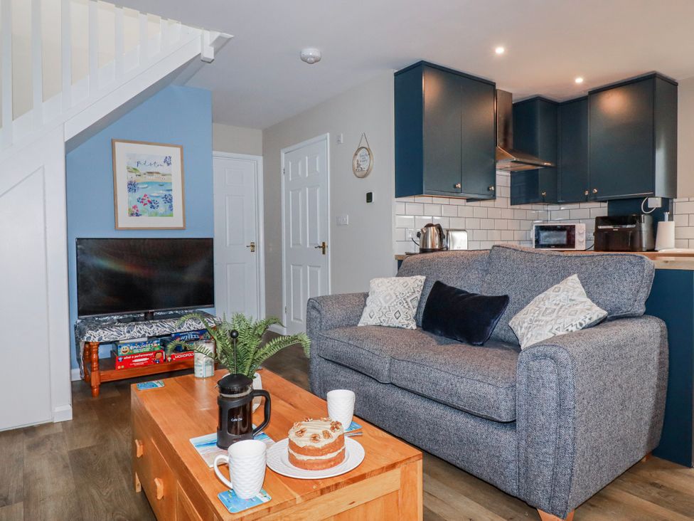 A living room with a sofa, coffee table, and television at Mayfly Lodge in St Tudy