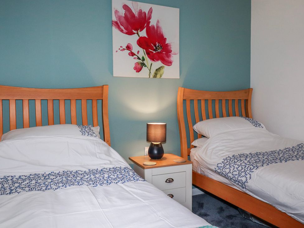 A bedroom with two beds and a lamp at Mayfly Lodge in St Tudy