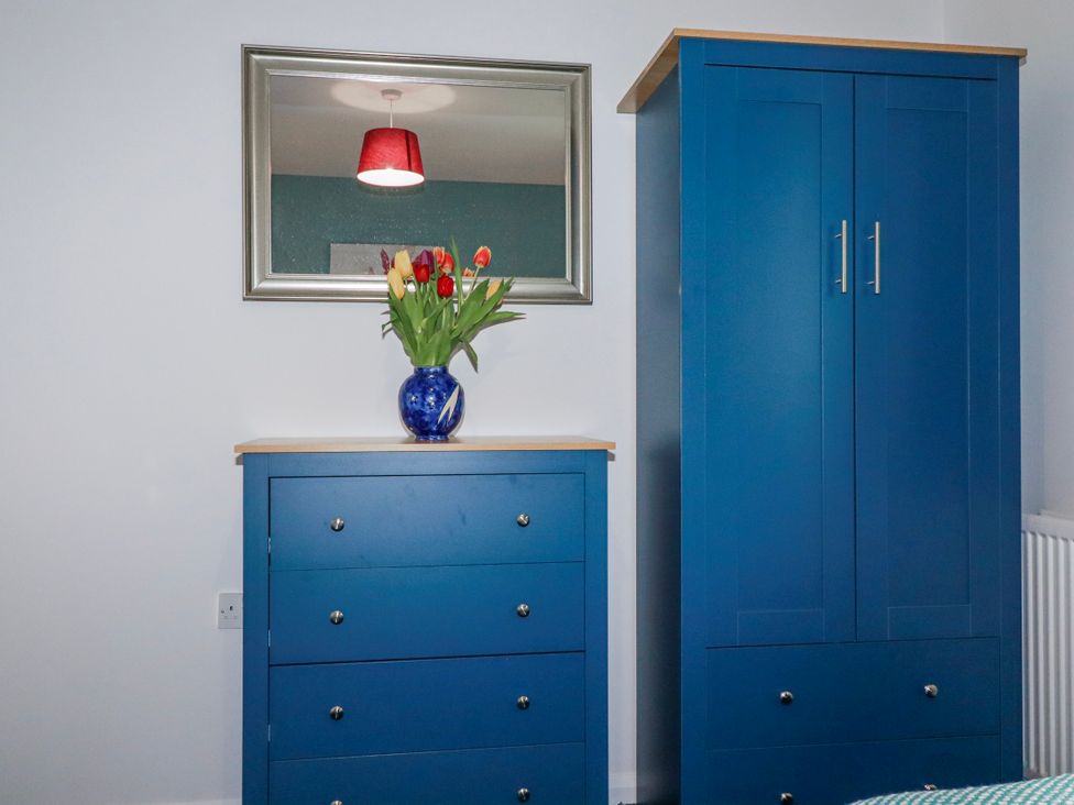 A bedroom with a wardrobe and chest of drawers at Mayfly Lodge in St Tudy