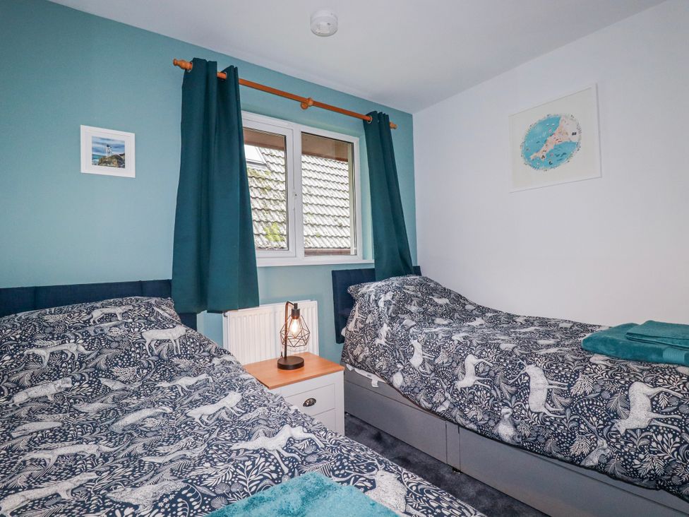 A bedroom with two single beds and a window at Mayfly Lodge St Tudy