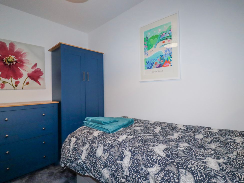 A bedroom with a bed and wardrobe at Mayfly Lodge in St Tudy