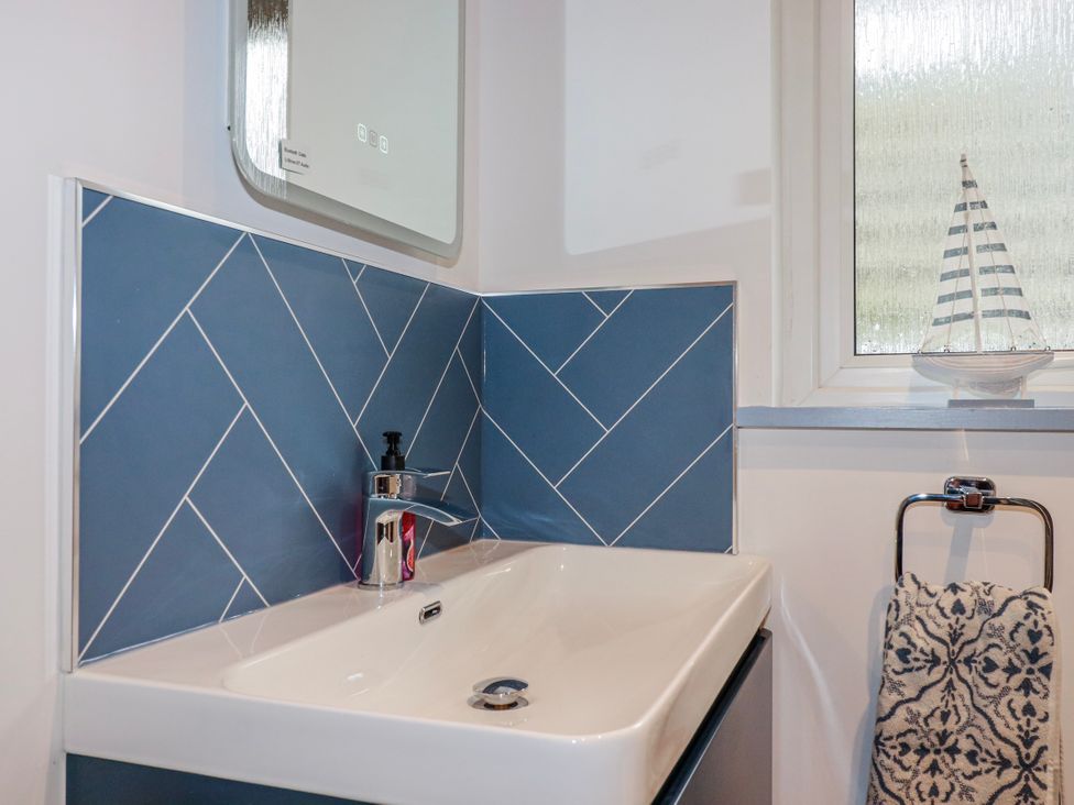 A bathroom with a sink faucet and a window at Mayfly Lodge in St Tudy