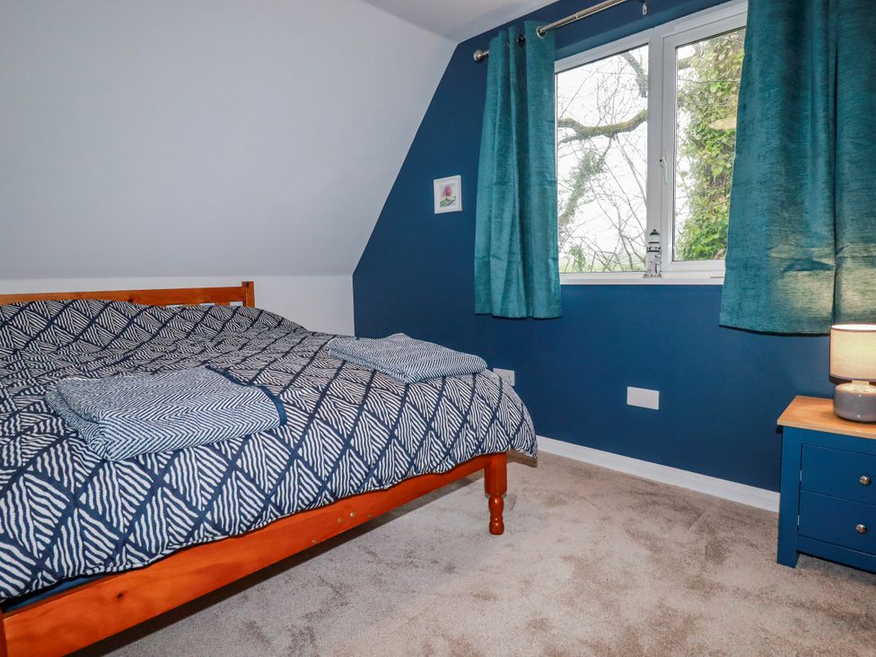 A bedroom with a bed and window at Mayfly Lodge in St Tudy