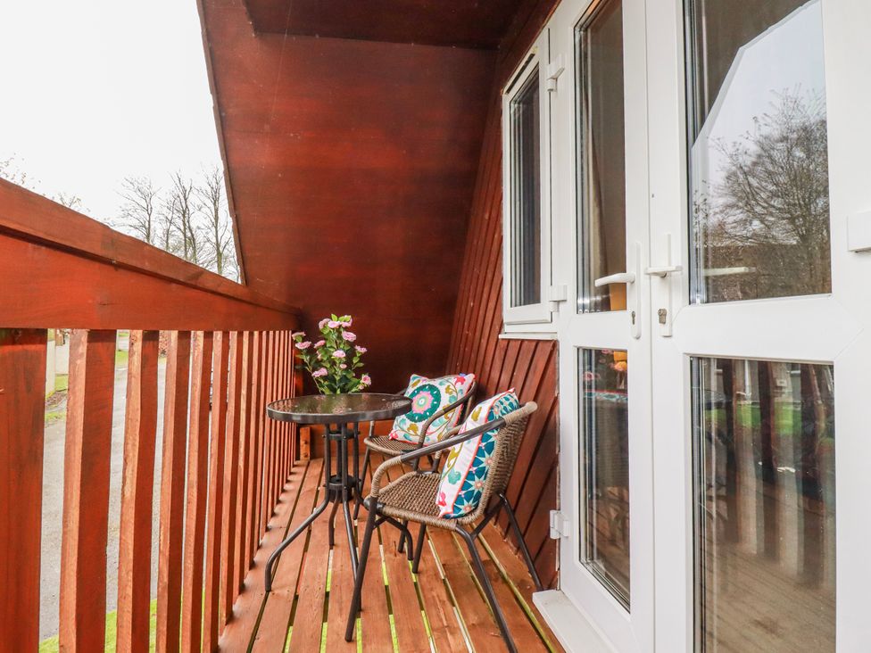 A balcony with table and chair at Mayfly Lodge in St Tudy