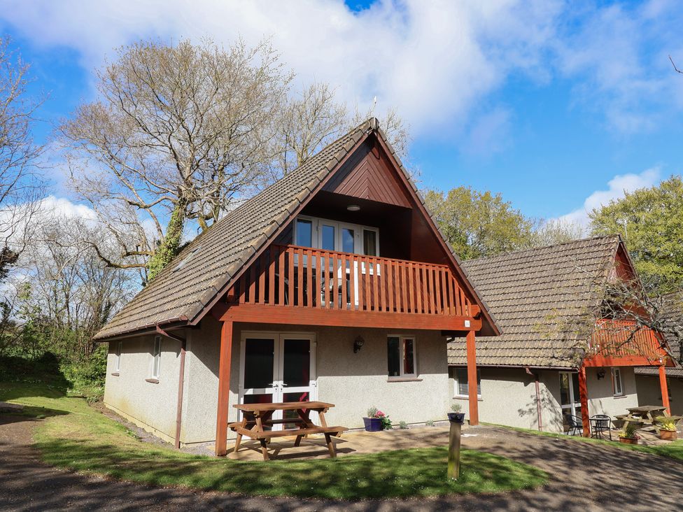A house with a balcony and outdoor seating area at Mayfly Lodge, St Tudy