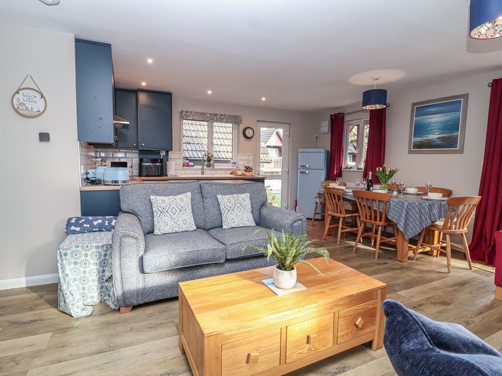 A living room with a dining area and kitchen at Mayfly Lodge in St Tudy