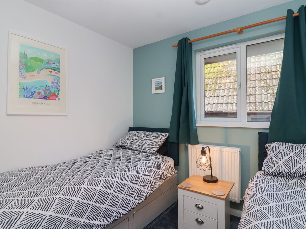 A bedroom with two beds and a nightstand at Mayfly Lodge in St Tudy