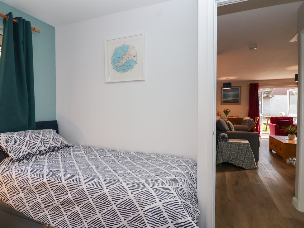 A bedroom with a bed and doorway leading to a living room at Mayfly Lodge St Tudy