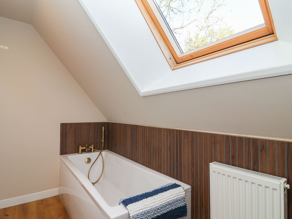 A bathroom with a bathtub and a skylight at Mayfly Lodge St Tudy
