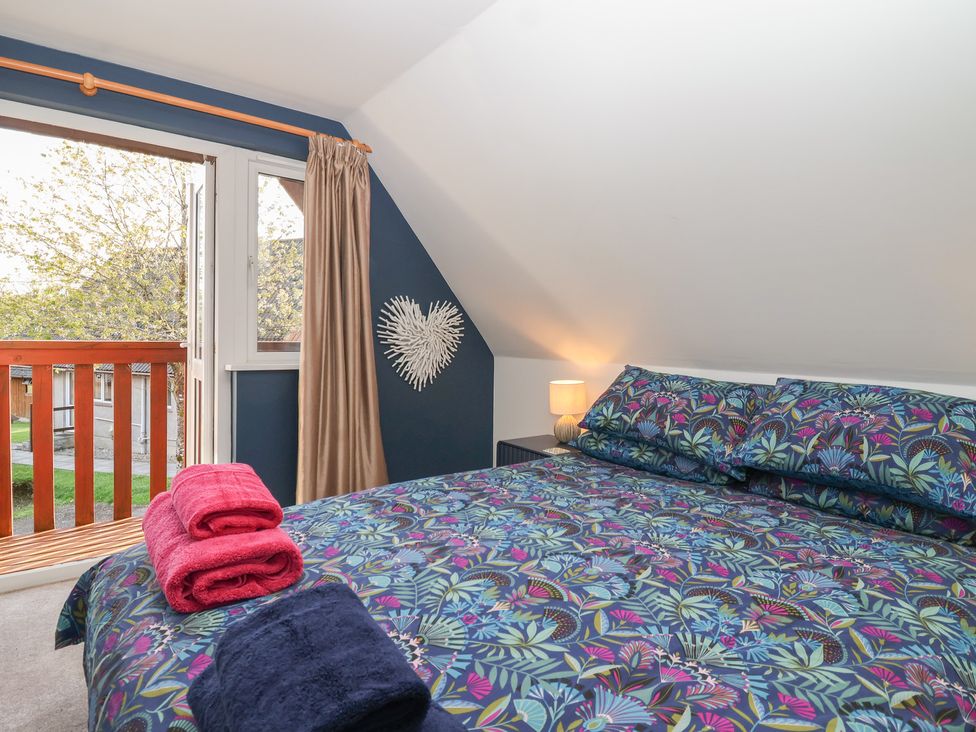 A bedroom with a bed and window at Mayfly Lodge in St Tudy