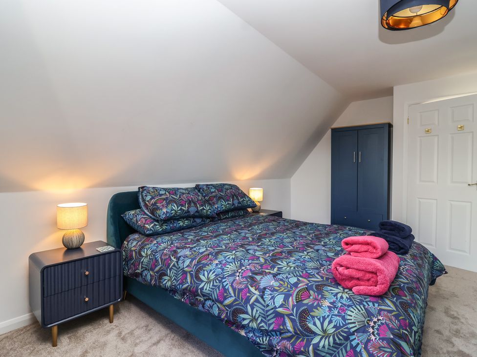 A bedroom with a bed and wardrobe at Mayfly Lodge St Tudy