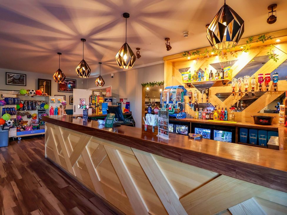 A bar with counters and shelves displaying drinks and toys at Mayfly Lodge St Tudy