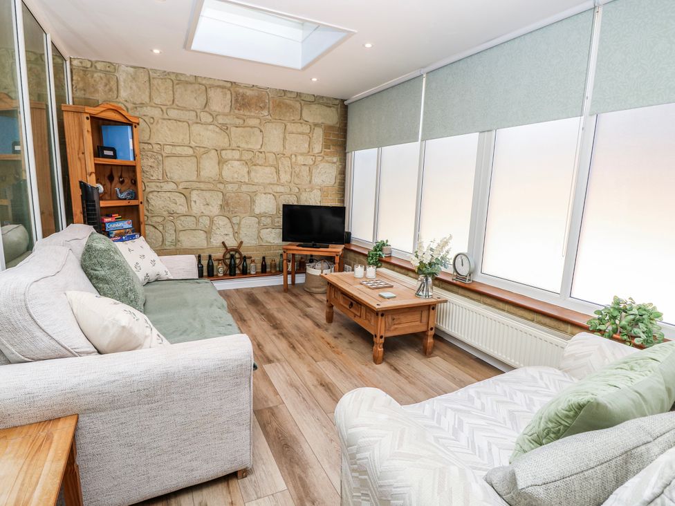 A snug with a sofa a coffee table and a television at 6 Priory in Shanklin