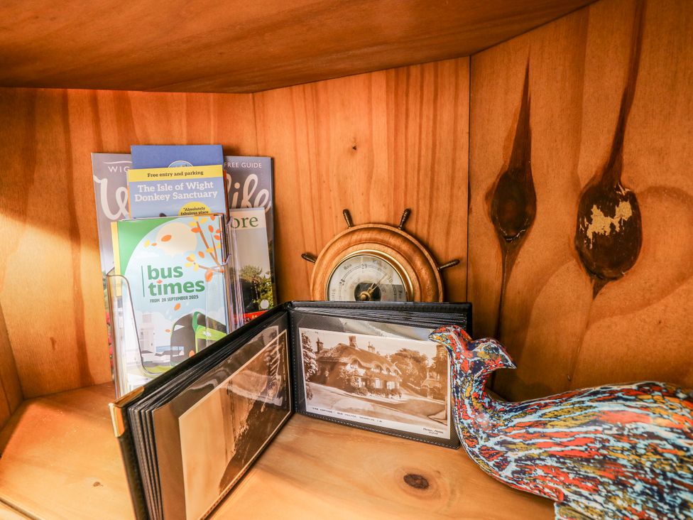 A wooden shelf with brochures, a photo album, a clock and a decorative bird at 6 Priory in Shanklin