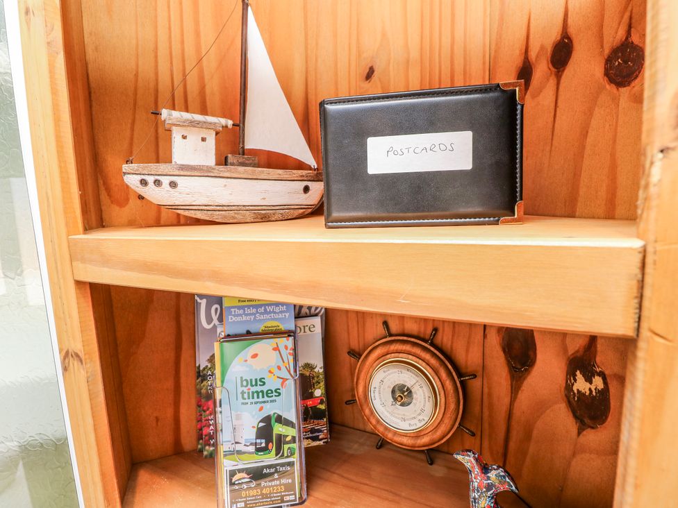 A shelf with a boat, postcards, a clock, and magazine at 6 Priory in Shanklin