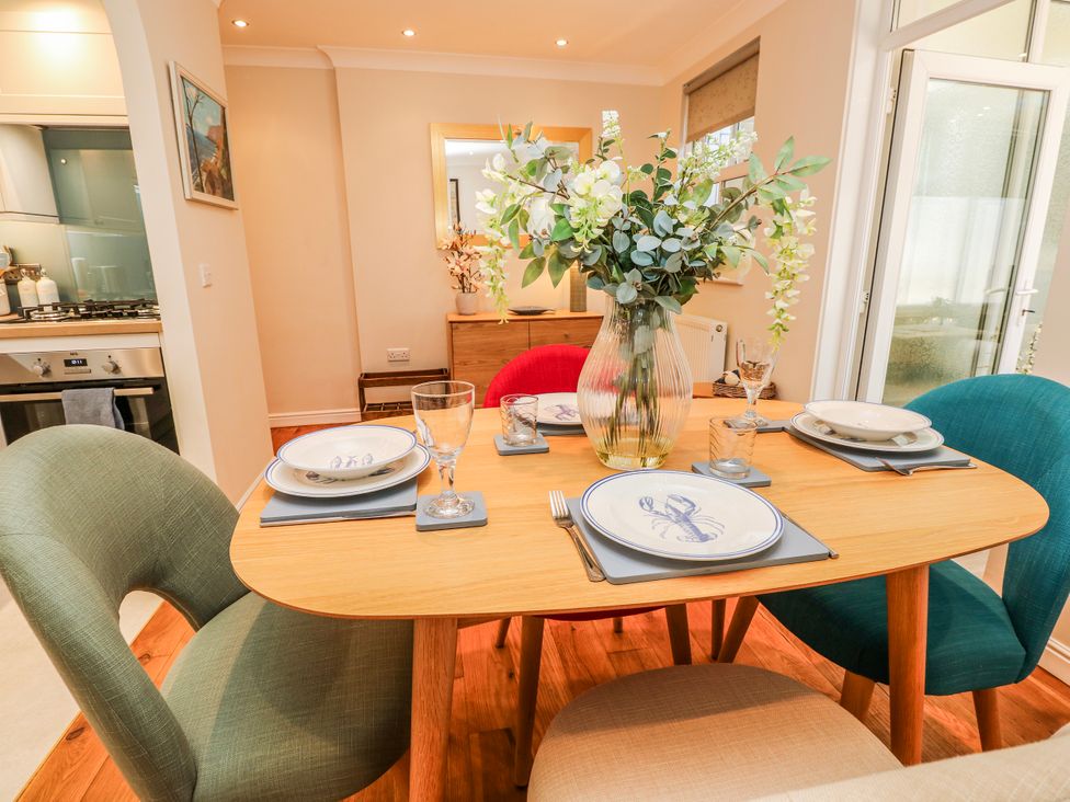A dining room with a table set for meals at 6 Priory in Shanklin