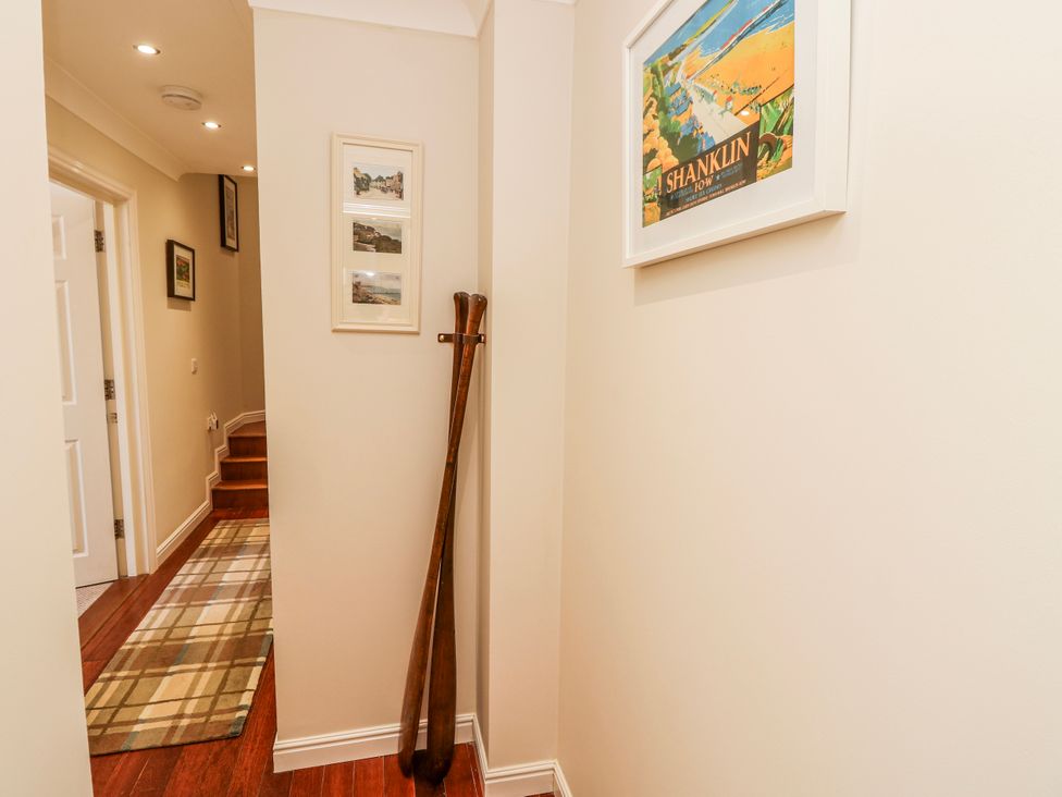 A hallway with stairs and pictures at 6 Priory in Shanklin