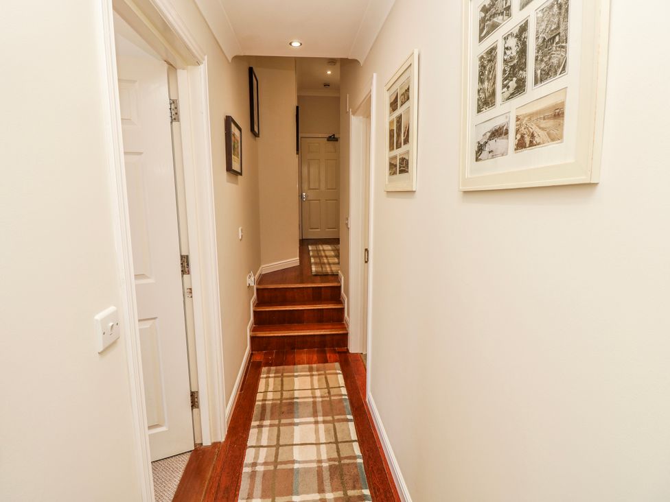 A hallway with steps and framed pictures at 6 Priory in Shanklin