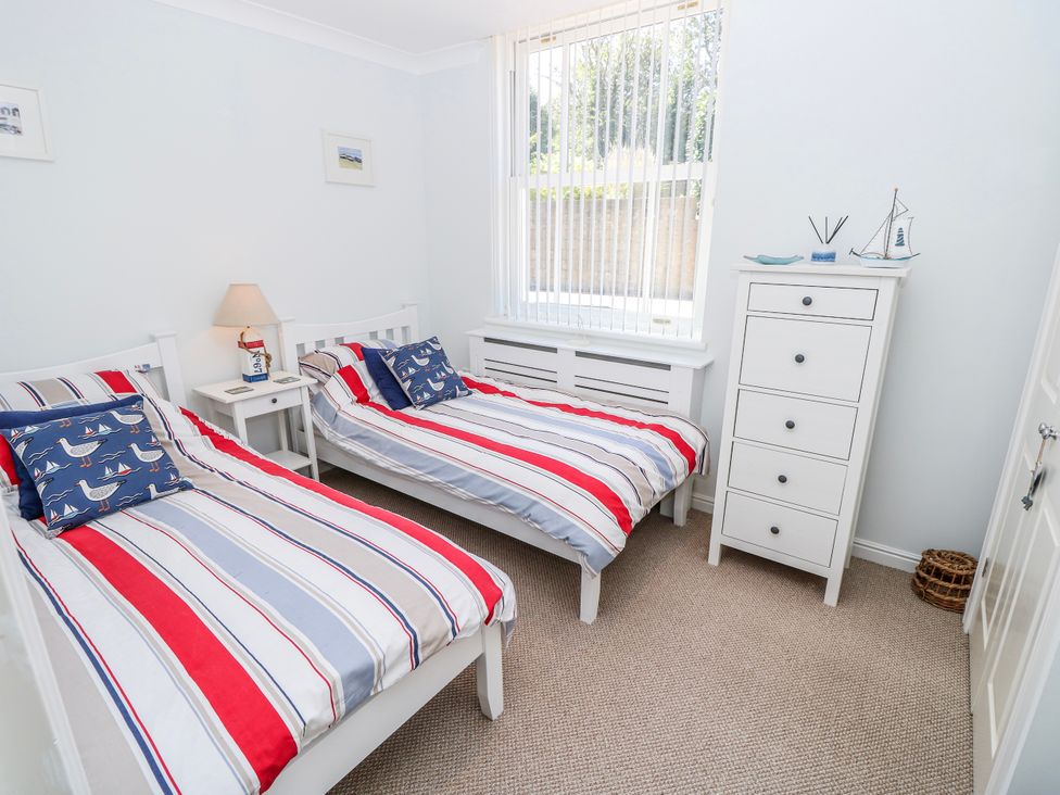 A bedroom with two beds and a dresser at 6 Priory in Shanklin