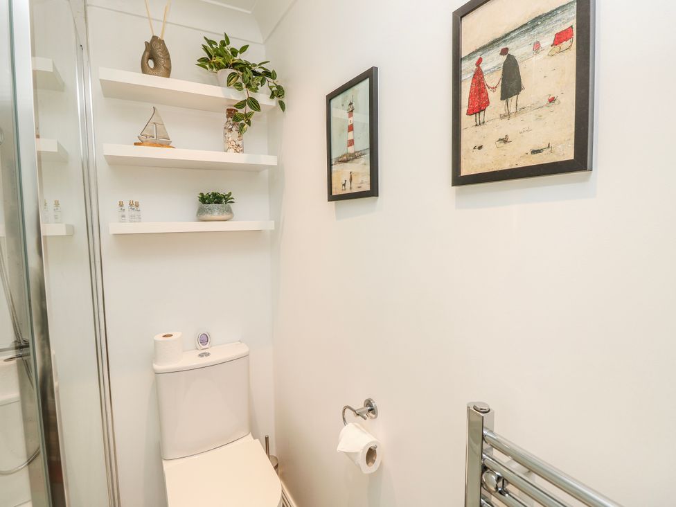 A bathroom with a toilet and shelves at 6 Priory in Shanklin