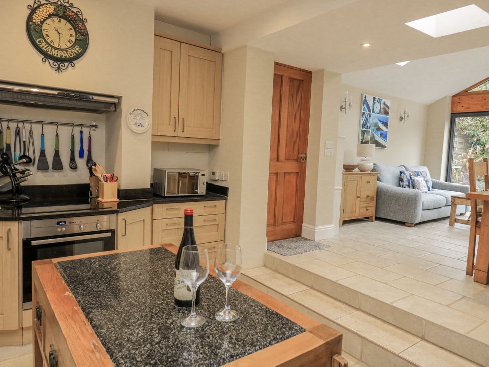 A kitchen with kitchen equipment and a sofa at Shipwrights in Salcombe