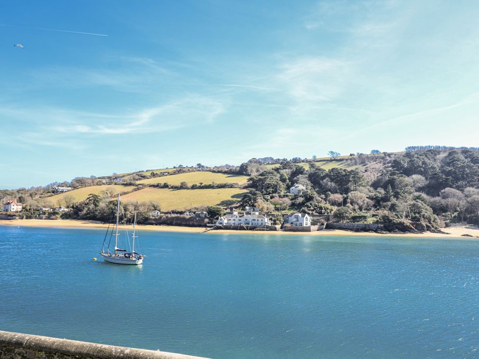 A coastal view with a boat on the water and houses by the hill at Shipwrights in Salcombe
