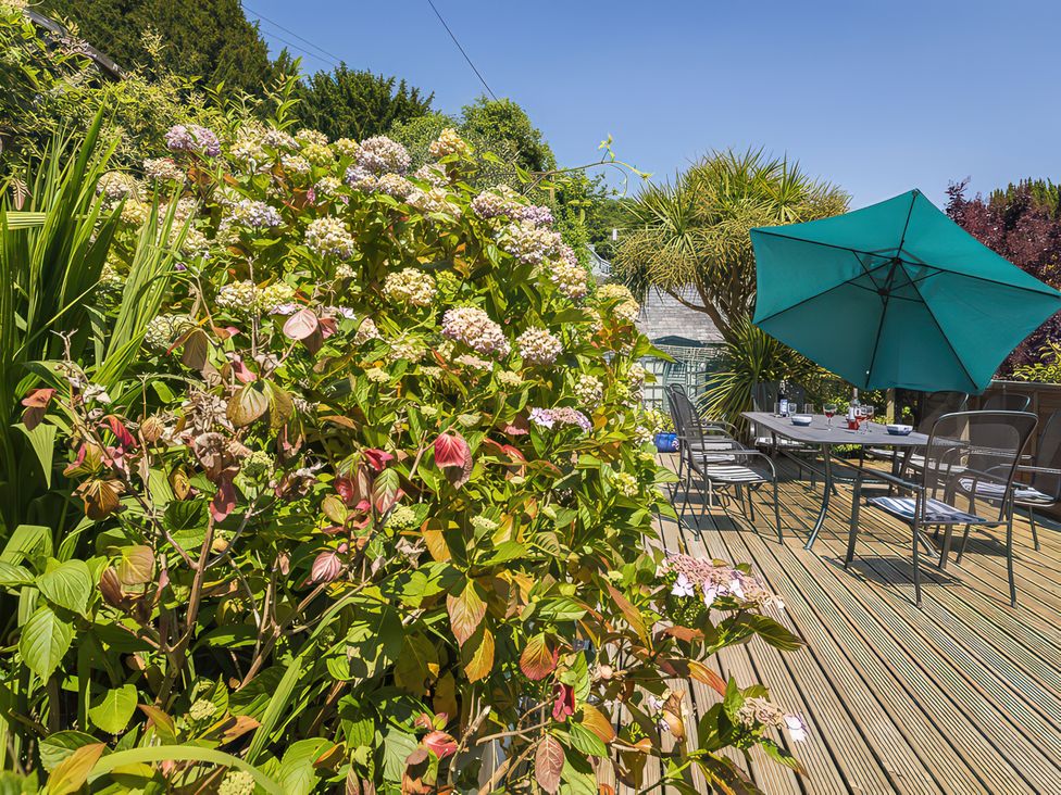 A garden with flowers and a table set with chairs at Shipwrights in Salcombe