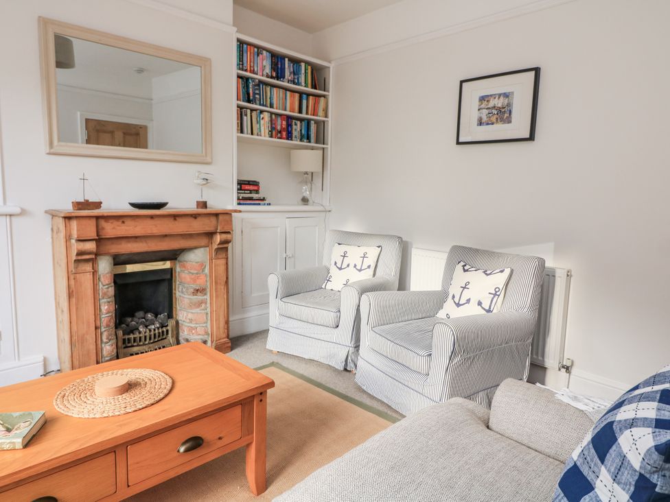 A living room with a fireplace and bookshelves at Shipwrights Coronation Road in Salcombe