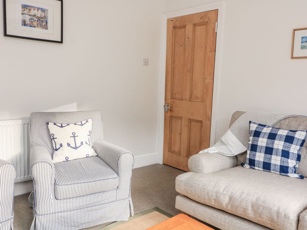 A living room with an armchair and a couch at Shipwrights Coronation Road in Salcombe