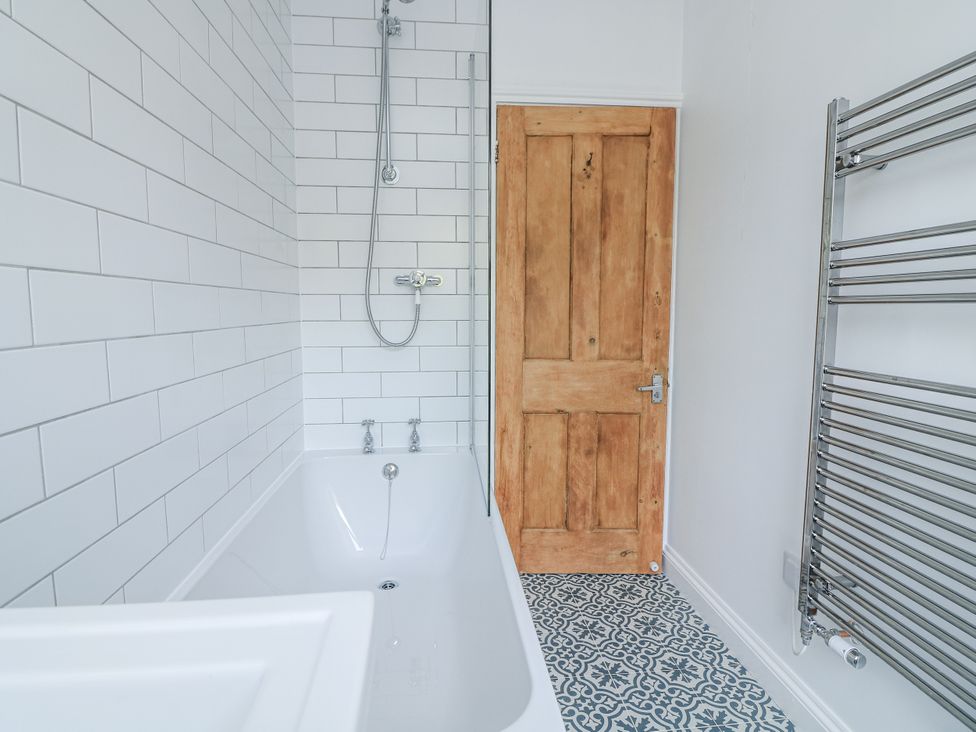A bathroom with a bathtub and shower equipment at Shipwrights Coronation Road in Salcombe