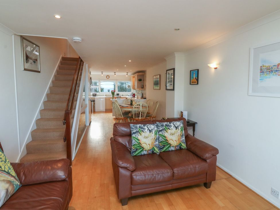 A living room with a staircase and kitchen view at 20 Heath Court in Brixham