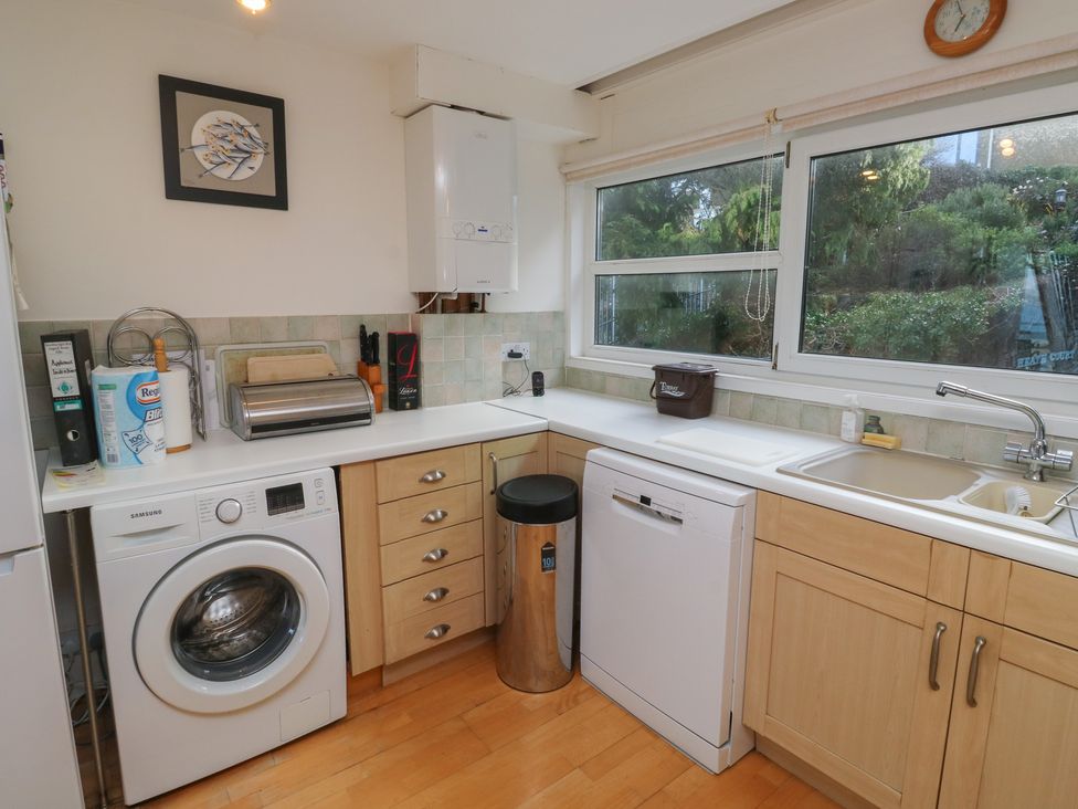 A kitchen with appliances including a washing machine and a dishwasher at 20 Heath Court Brixham