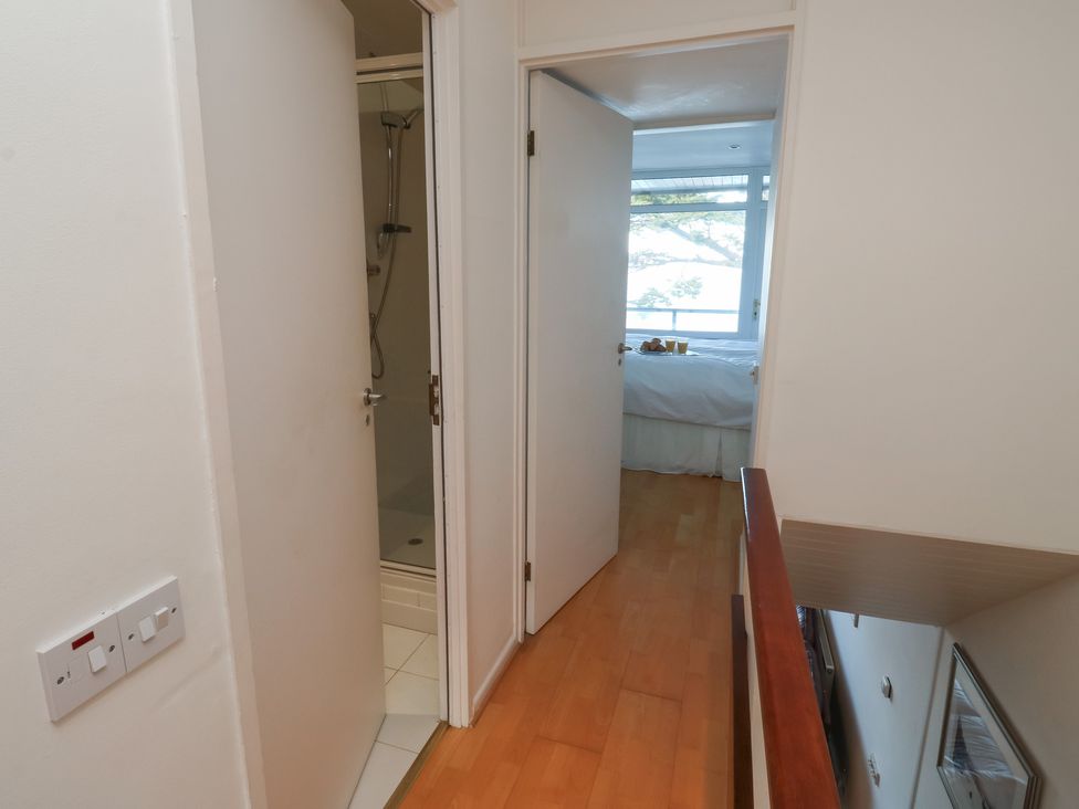 A hallway with doors leading to a shower and bedroom at 20 Heath Court in Brixham