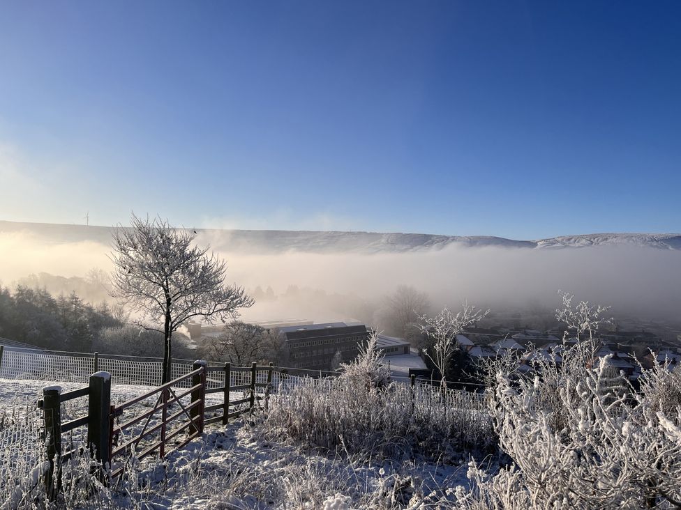 A landscape with a tree and fog covering buildings in the valley at The Cabin in Crawshawbooth