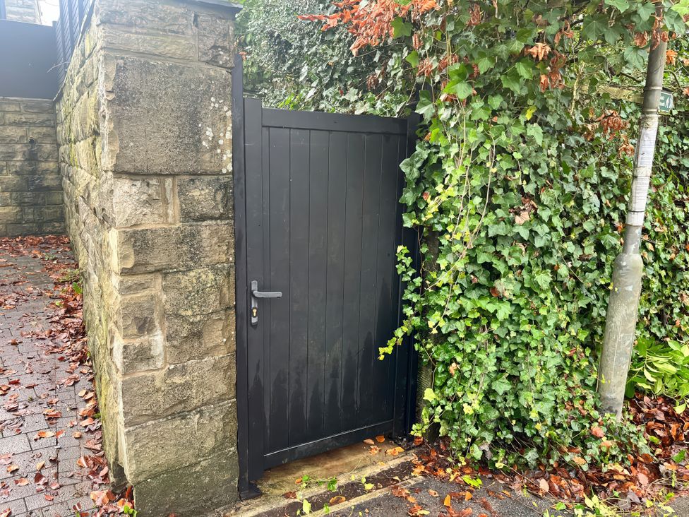A gate next to a stone wall covered in ivy in a garden at The Cabin in Loveclough near Crawshawbooth