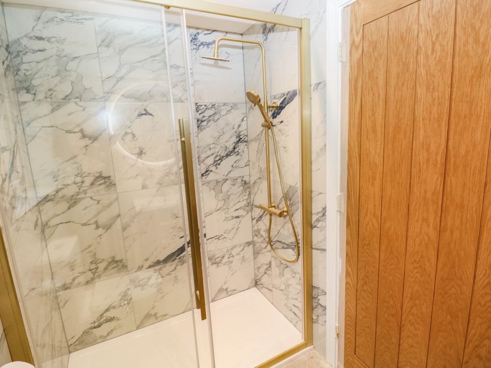 A shower with glass door and marble walls at Hawthorns