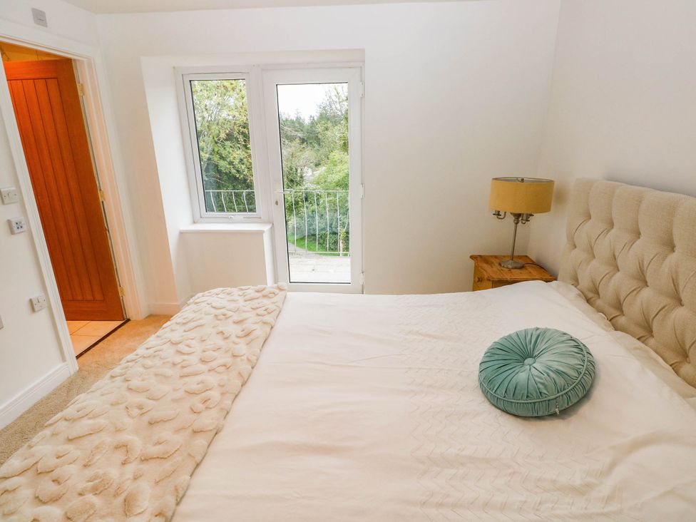 A bedroom with a bed and a door leading to a balcony at Hawthorns