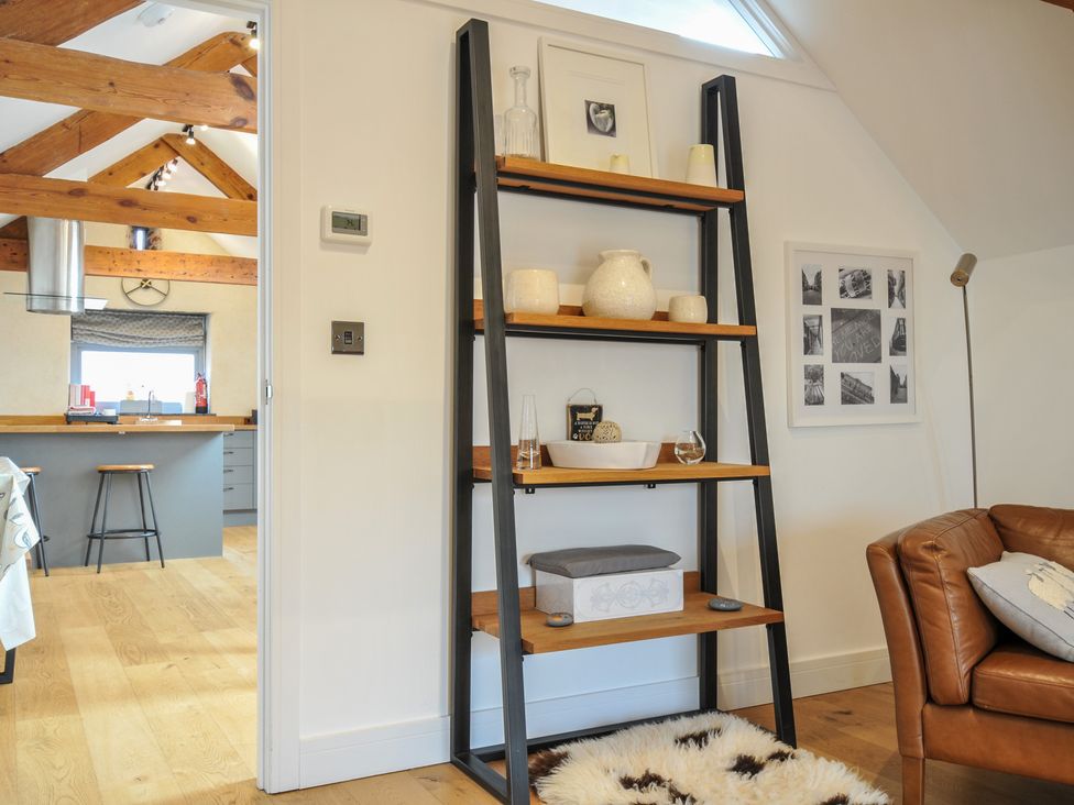A living room with a shelf displaying decor and a kitchen in the background at The Dairy