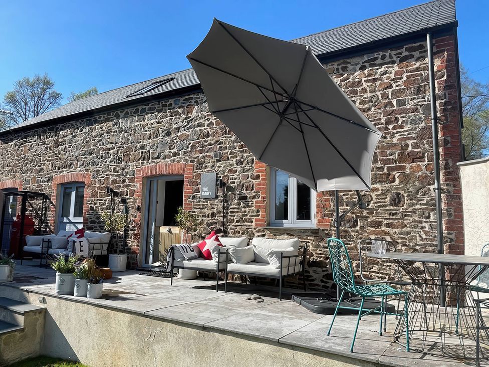 An outdoor area with seating and an umbrella at The Dairy in Bridgerule