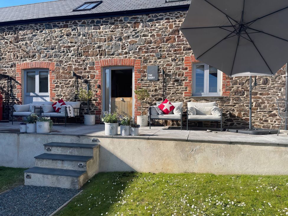 An outdoor seating area with planters and an umbrella at The Dairy in Bridgerule