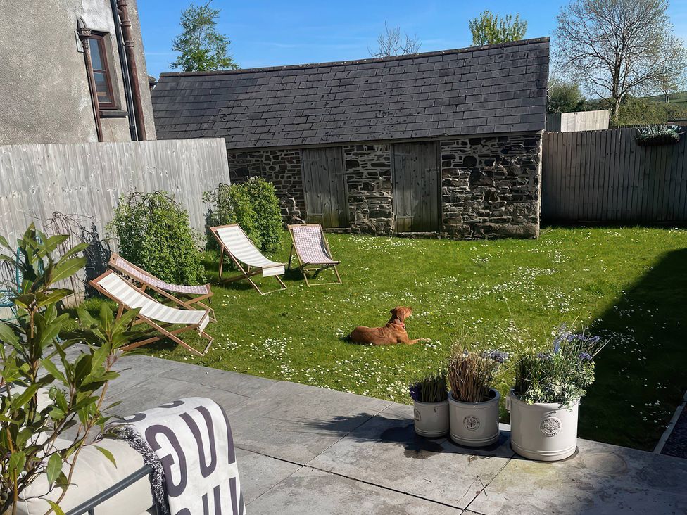 A garden with chairs and a dog at The Dairy in Bridgerule