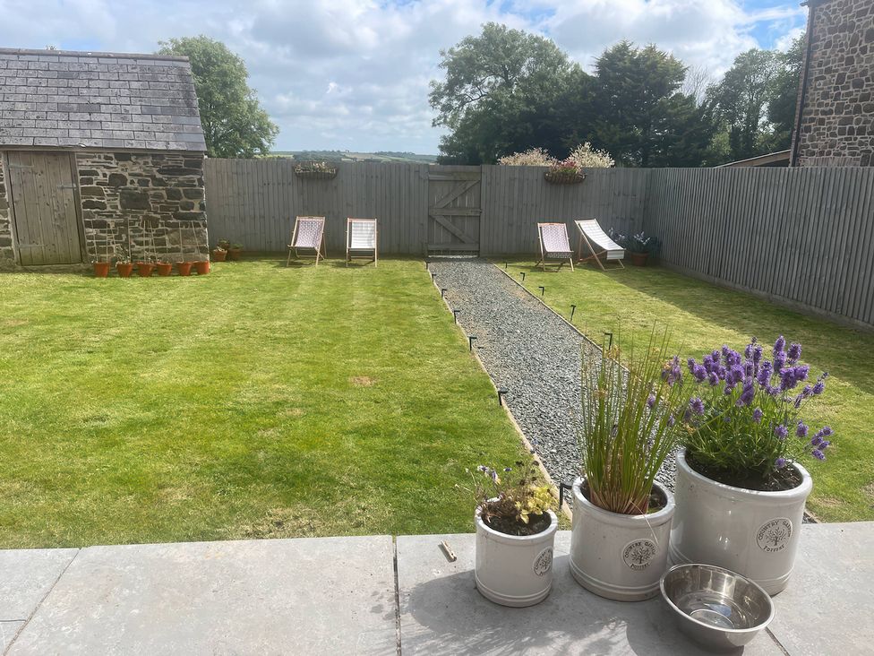 A garden with a lawn, deck chairs, and a shed at The Dairy in Bridgerule