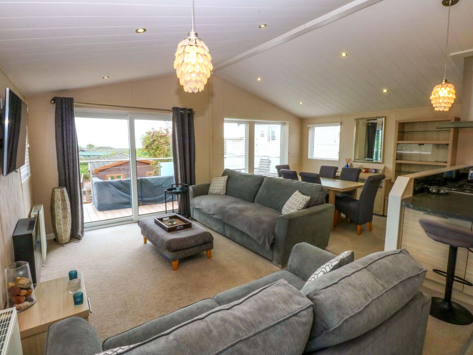 A living room with a sofa and dining area at The Hideaway in Pwllheli