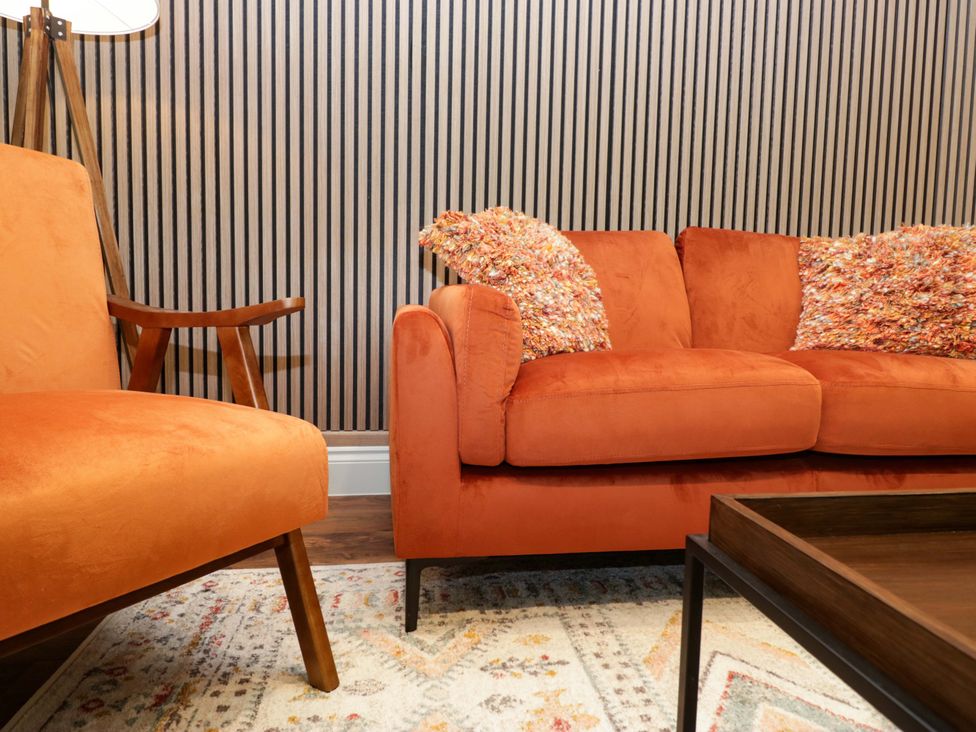 A living room with orange sofa and armchair at The Studio in Windermere