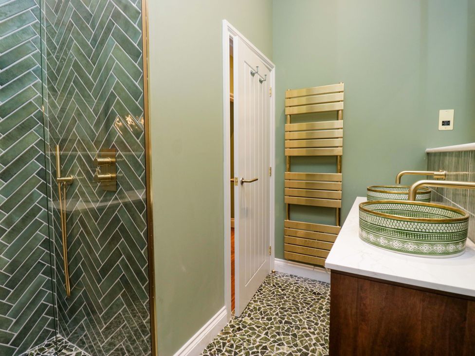 A bathroom with a shower, sink, and towel rack at The Studio in Windermere