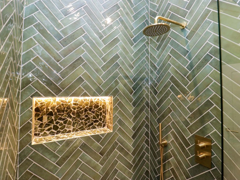 A bathroom with a shower and green tiled walls at The Studio in Windermere