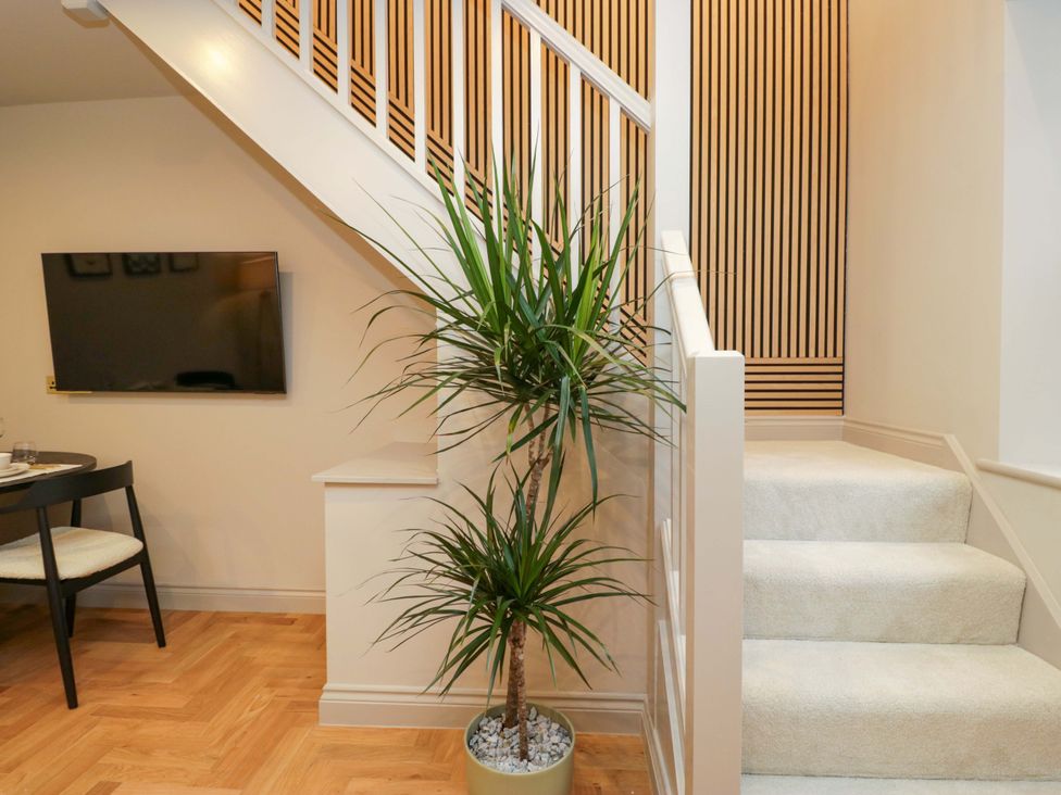 A staircase with a plant and television in the entryway at The Coach House Windermere