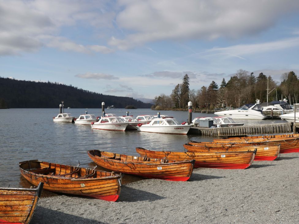 Boats on a shoreline with water and trees at The Coach House in Windermere