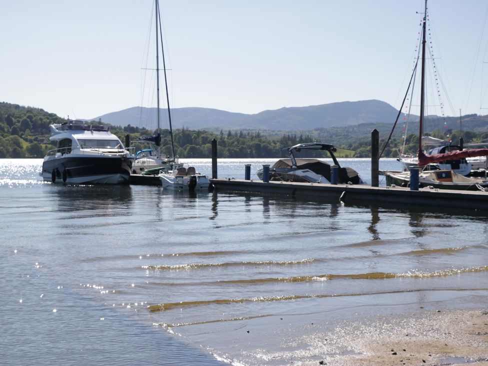 A scene of boats at a dock with mountains in the background at The Coach House in Windermere