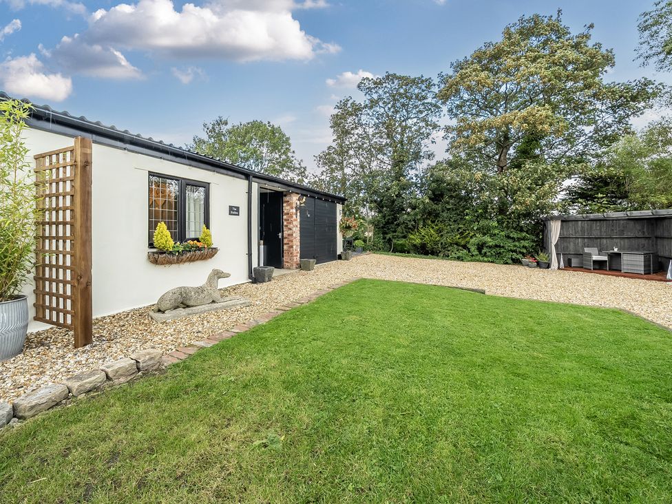 An exterior view of a building with a lawn and outdoor seating at The Stables in Poulton-le-Fylde